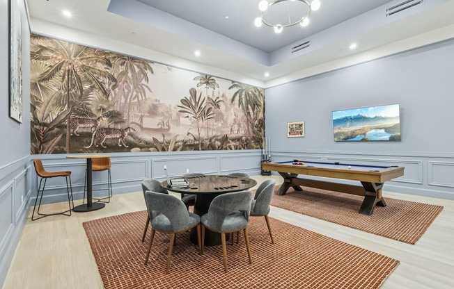 A room with a pool table and a jungle mural on the wall.