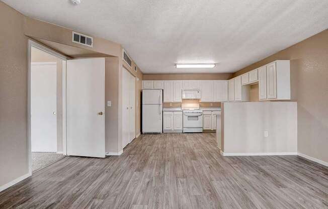 A kitchen with white cabinets and a white fridge.