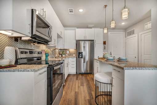 A modern kitchen with white cabinets and stainless steel appliances.