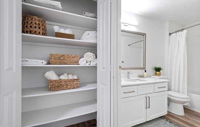 a white bathroom with open shelving and a white toilet and sink