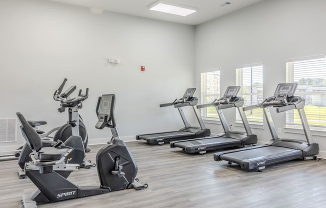 a gym with several treadmills and ellipticals on the floor