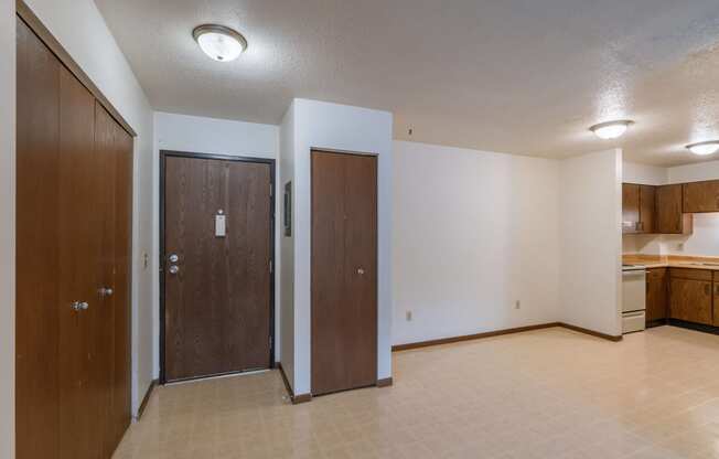 an entry door with a couple closets and a dining room and kitchen in the background. Moorhead, MN South Park Apartment