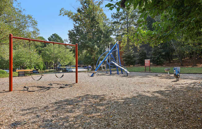 A playground with a swing set and a blue slide.