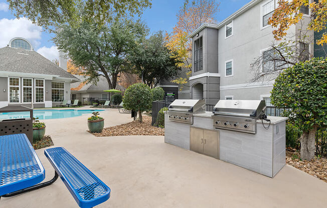 Outdoor BBQ Area with Furniture and Pool View at Bridges at Oakbend Apartments in Lewisville, TX.