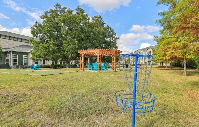 A blue disc golf basket sits in a grassy field.