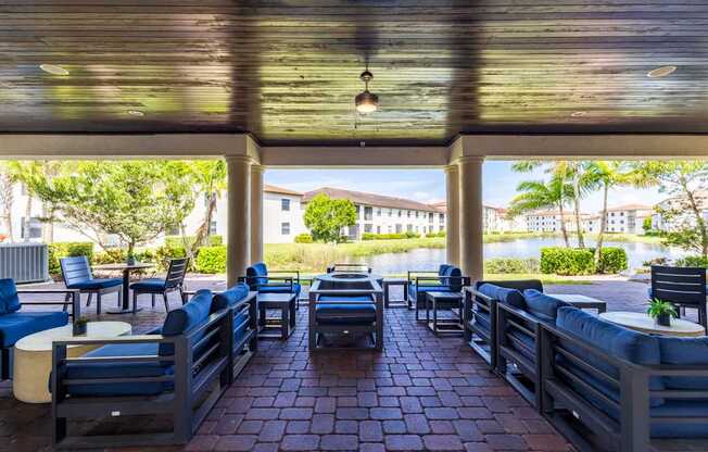 A patio with blue chairs and tables overlooking a body of water.