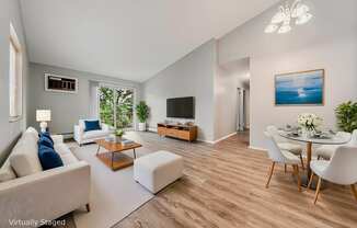 A living room with a white couch, a coffee table, a TV, and a painting on the wall.