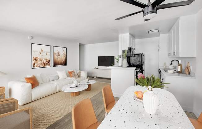 A modern living room with a white sofa, a white dining table, and a ceiling fan.