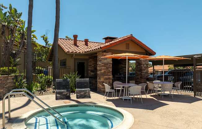 a jacuzzi and patio with tables and chairs in front of a house