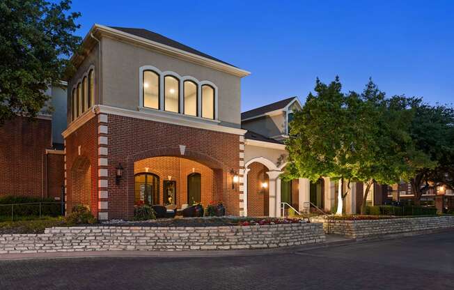 A house with a red brick facade and white trim is shown at dusk.