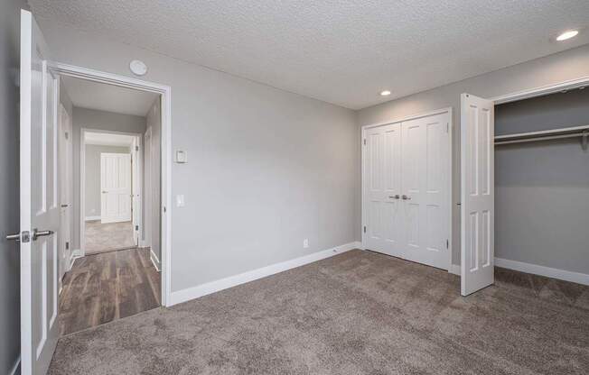 A room with a carpeted floor and two doors.