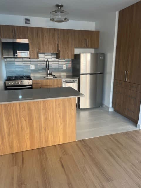 A kitchen with wooden cabinets and a stainless steel refrigerator.
