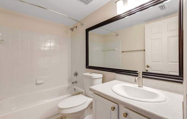 A white bathroom with a toilet, sink, and bathtub.