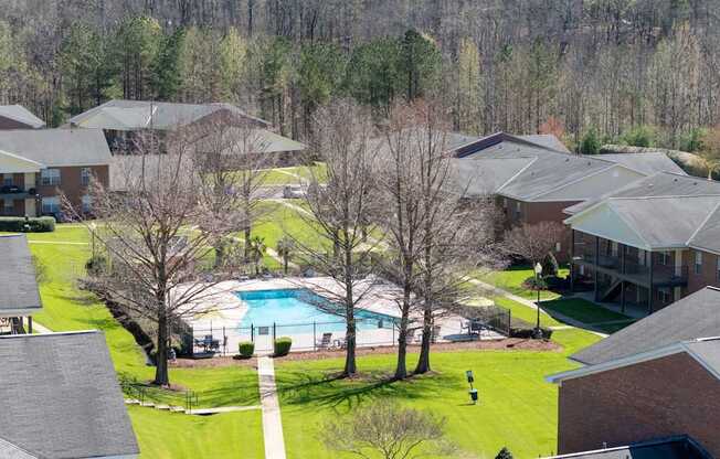 A swimming pool is surrounded by houses and trees.