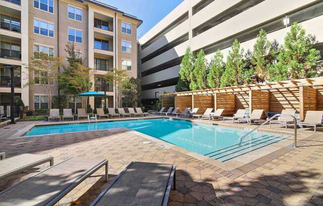 A swimming pool surrounded by lounge chairs and trees.