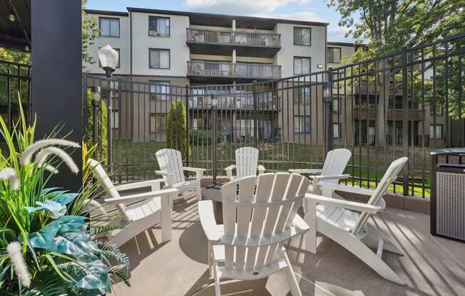 A patio with white chairs and a table is in front of a building.