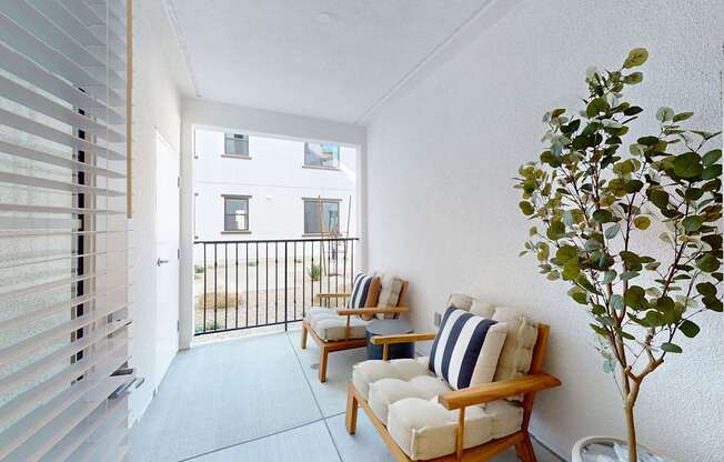 A balcony with two chairs and a table with a tree in a pot at The Villas at Anacapa Canyon, Camarillo, 93012