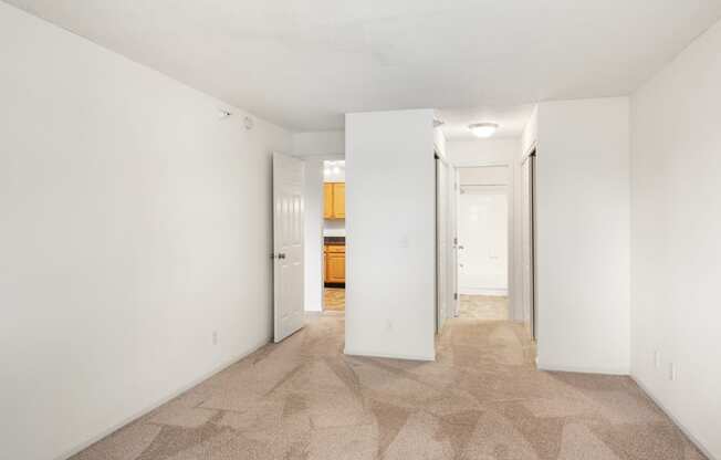 a spacious living room with white walls and a carpeted floor