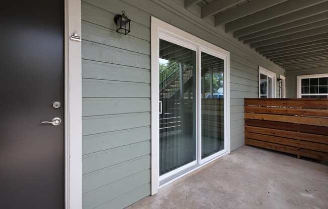 Outside view of front door, sliding glass door to patio, and privacy fence