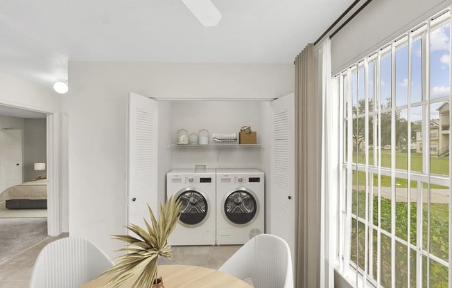 a dining area with a table and chairs and a washer and dryer in a laundry