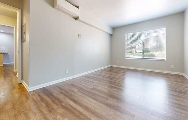 an empty living room with wood floors and a window