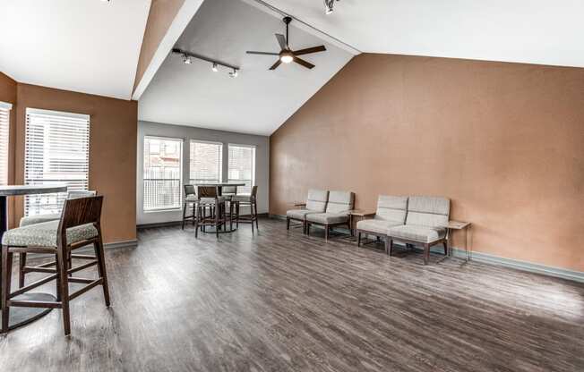 an empty living room with chairs and a dining room table and a ceiling fan