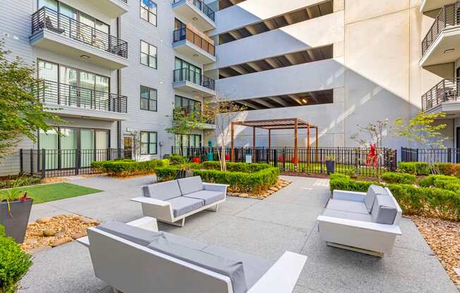 A modern outdoor seating area with grey couches and a black fence.