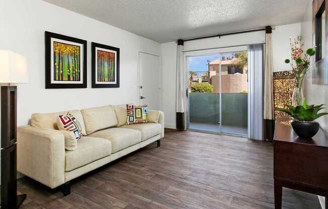 A living room with a couch, two pictures on the wall, and a sliding glass door.
