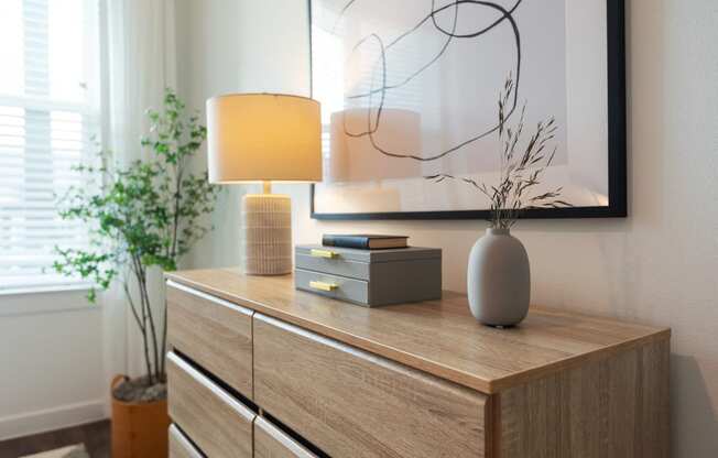 a wooden dresser with a lamp and a vase on it