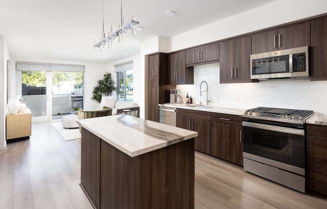 A modern kitchen with dark wood cabinets and stainless steel appliances. at Elements Apartments*, Irvine, CA