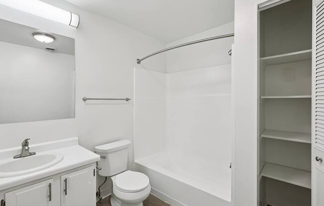 A white bathroom with a toilet, sink, and shower.