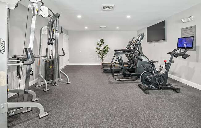 a gym with exercise equipment and a tv on the wall