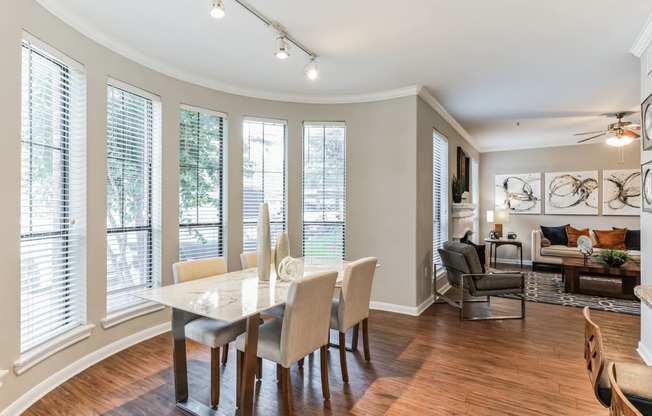 a dining room with a table and chairs and a living room with windows