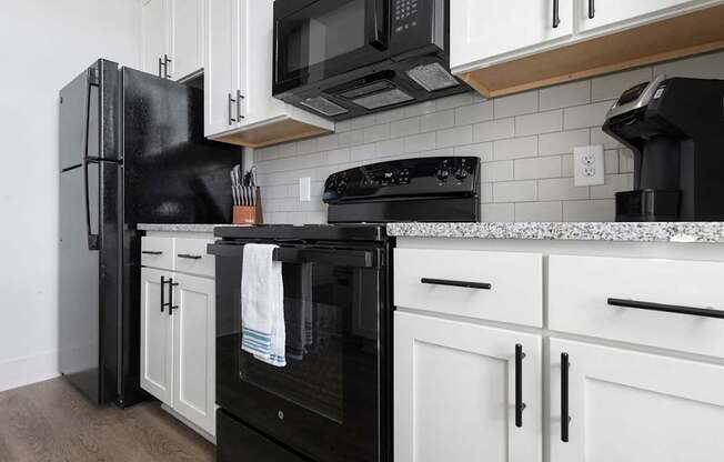 A black refrigerator stands next to a black oven in a kitchen.