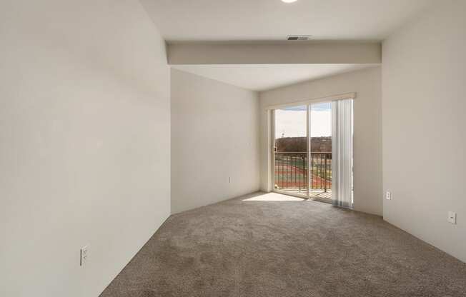 A living room with white walls, taupe carpets, and sunny sliding glass doors to balcony.at Shoreline Village, Richland, WA 99352