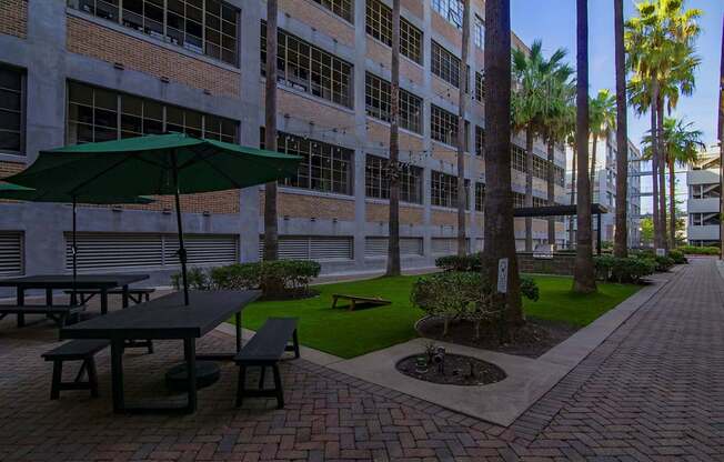 A patio with a table and benches is surrounded by a brick wall and palm trees.