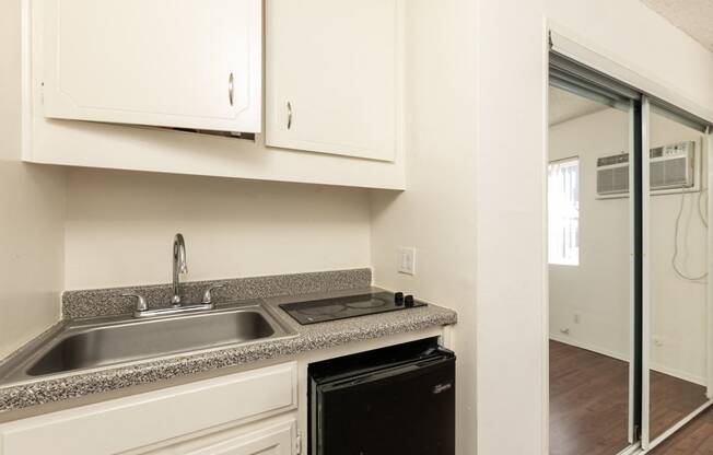 Studio with Hardwood Floors, Mirrored Wardrobe Closet and Kitchen with White Cabinets