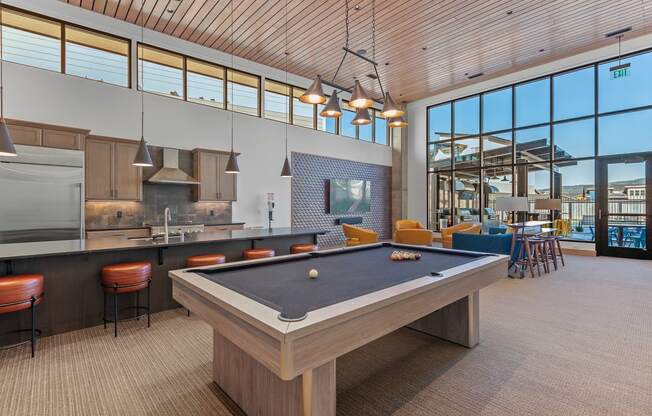 a pool table in a clubhouse with a kitchen and bar