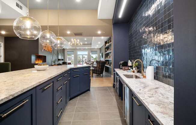 A modern kitchen with dark blue cabinets and marble countertops.