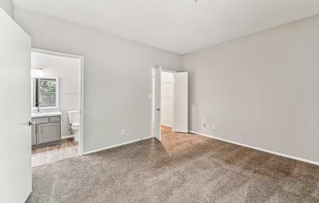 an empty living room with carpet and a bathroom