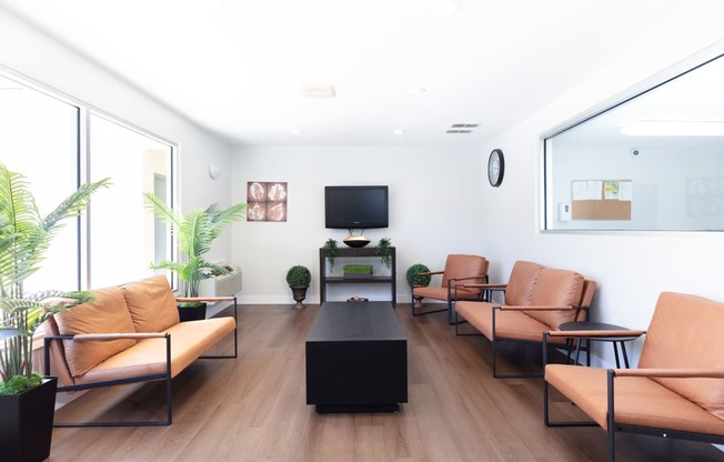 a waiting room with leather chairs and a table and a television