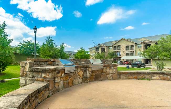 a stone retaining wall with a driveway and a building in the background