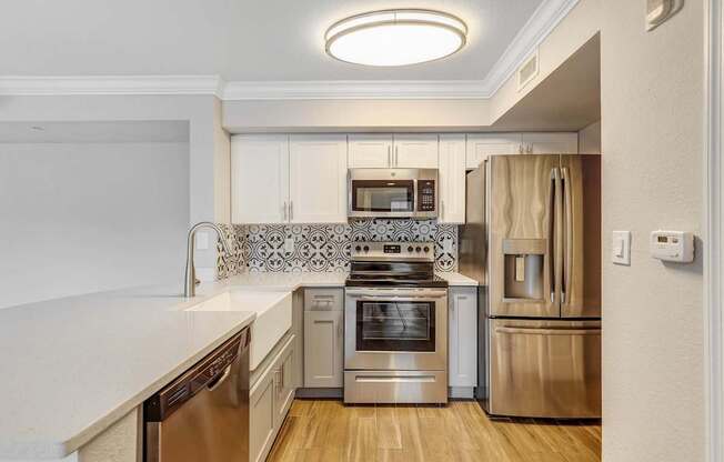 A modern kitchen with stainless steel appliances and wooden floors.