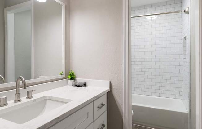 A white bathroom with a sink, mirror at Dunwoody Glen, Atlanta