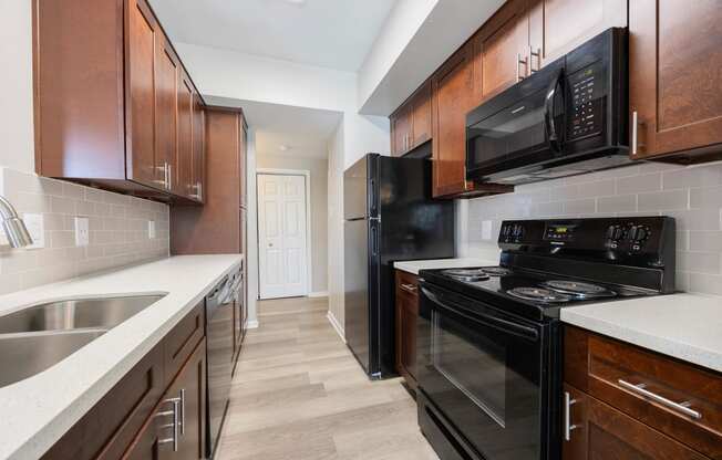 a kitchen with black appliances and wooden cabinets and white counter tops