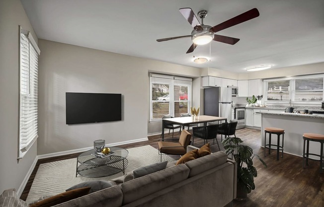 a living room and kitchen with a ceiling fan and a flat screen tv