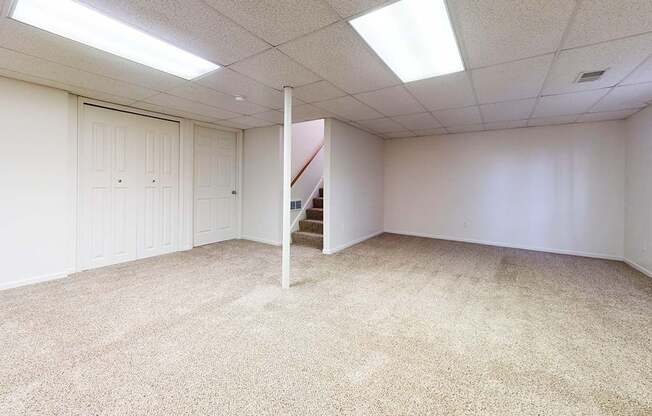 A basement recreation room with white walls and carpeted floor at Foxwood and The Hermitage, Michigan