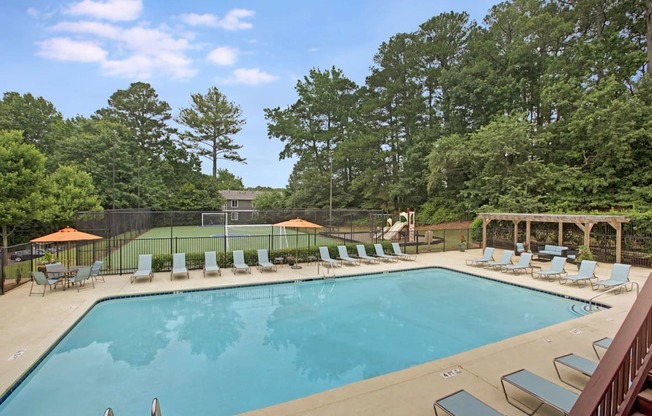 A large swimming pool surrounded by trees and lounge chairs.