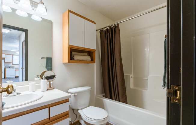 a bathroom with a shower toilet and sink and a mirror. Fargo, ND Eagle Run Apartments