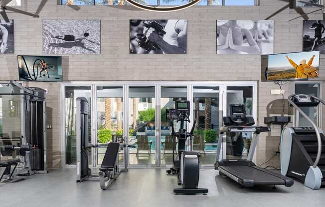 a gym with cardio equipment and pictures on the wall